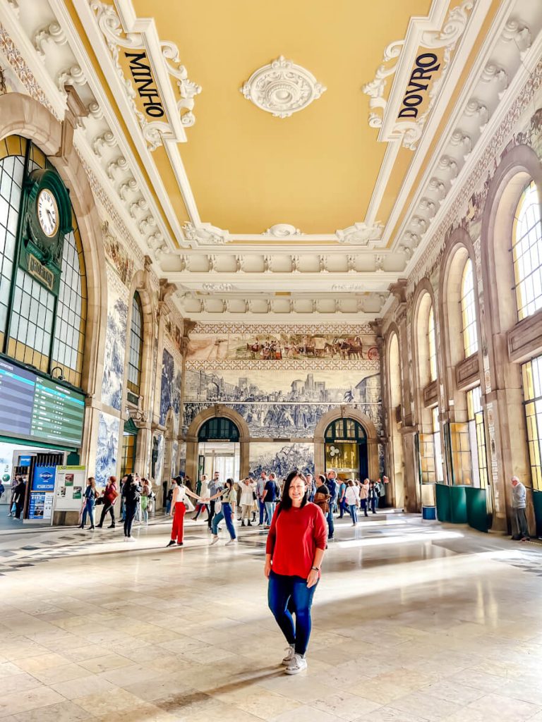 Girl posing in front of the blue tiled interior of São Bento train station in Porto, Portugal