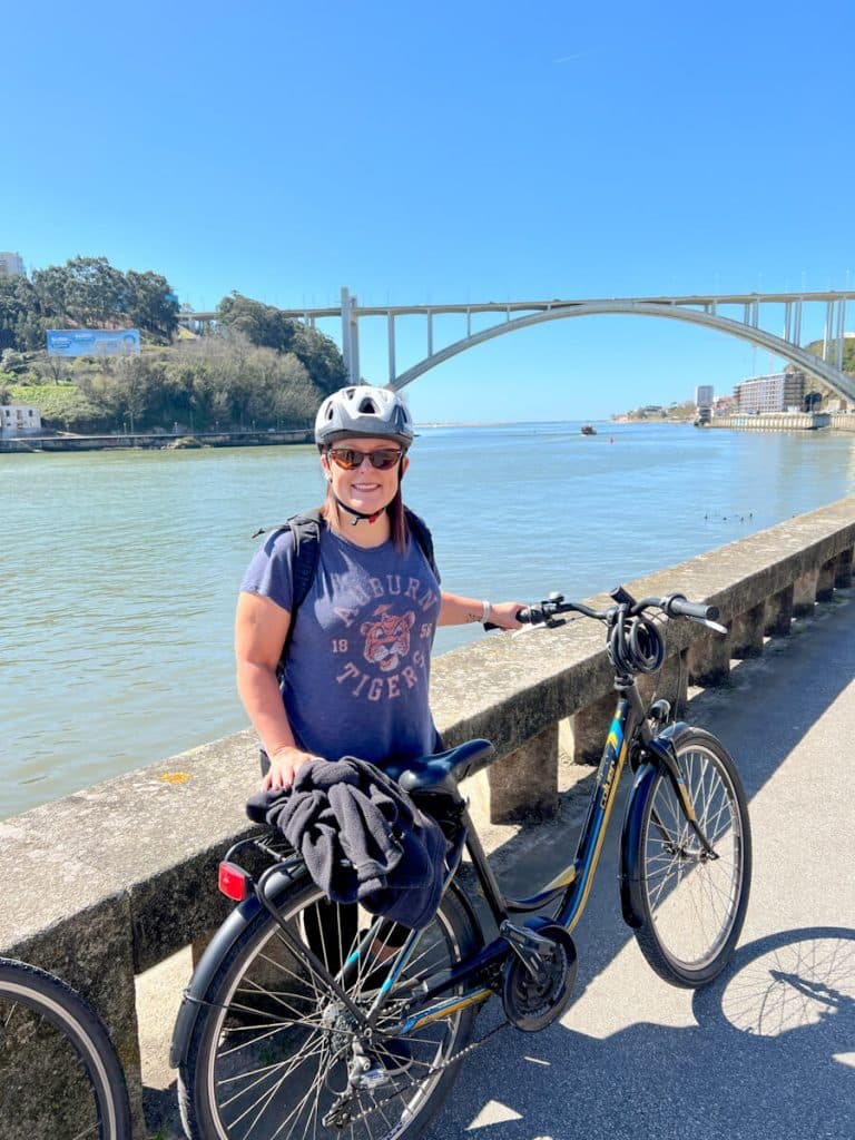 Woman posing with bike along The Douro River in Porto, Portugal