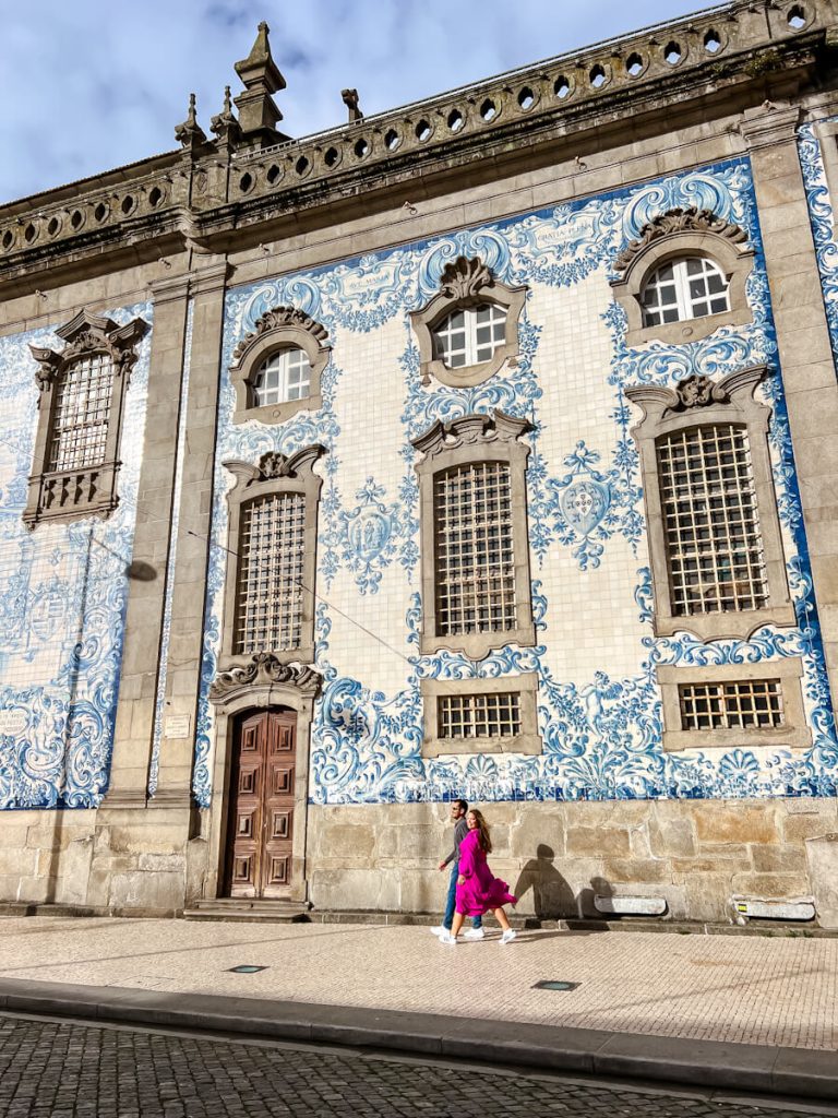 Couple walking past blue and white tiled Igreja do Carmo in Porto, Portugal