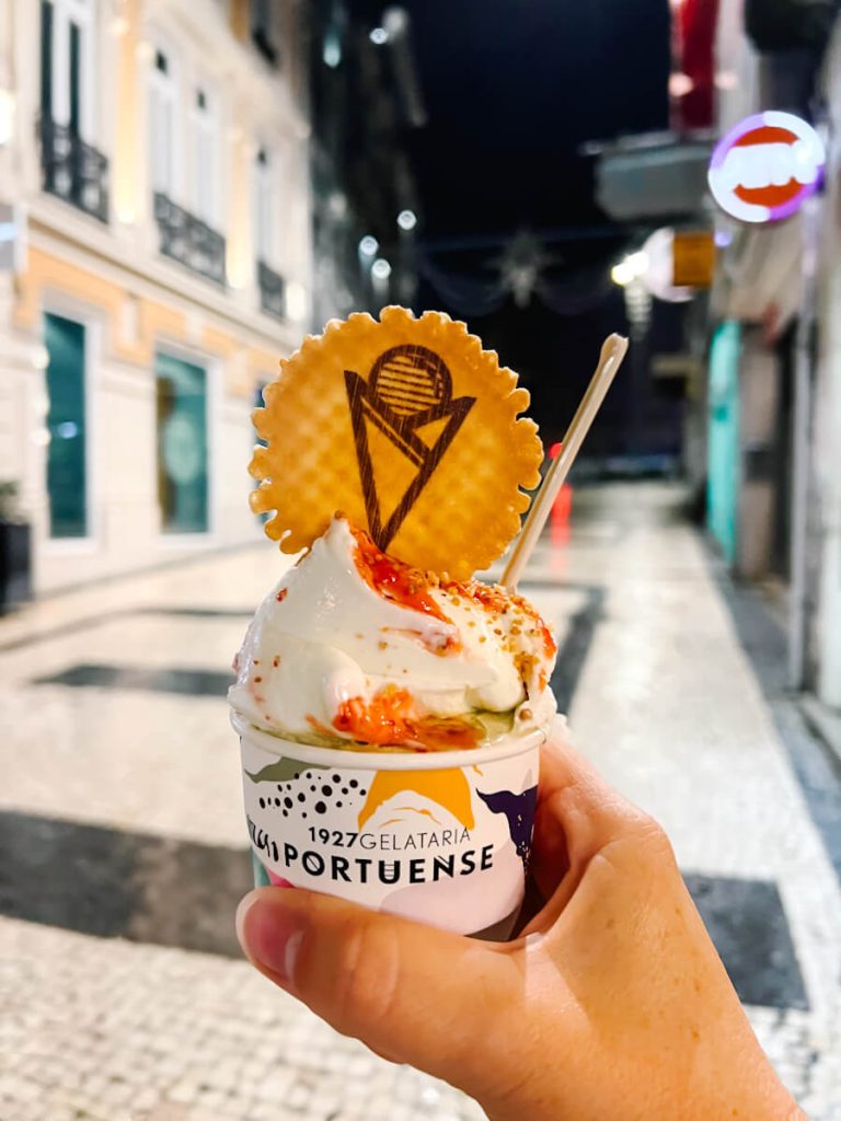 Scoop of strawberry cheesecake gelato in a cup with a wafer cookie on top