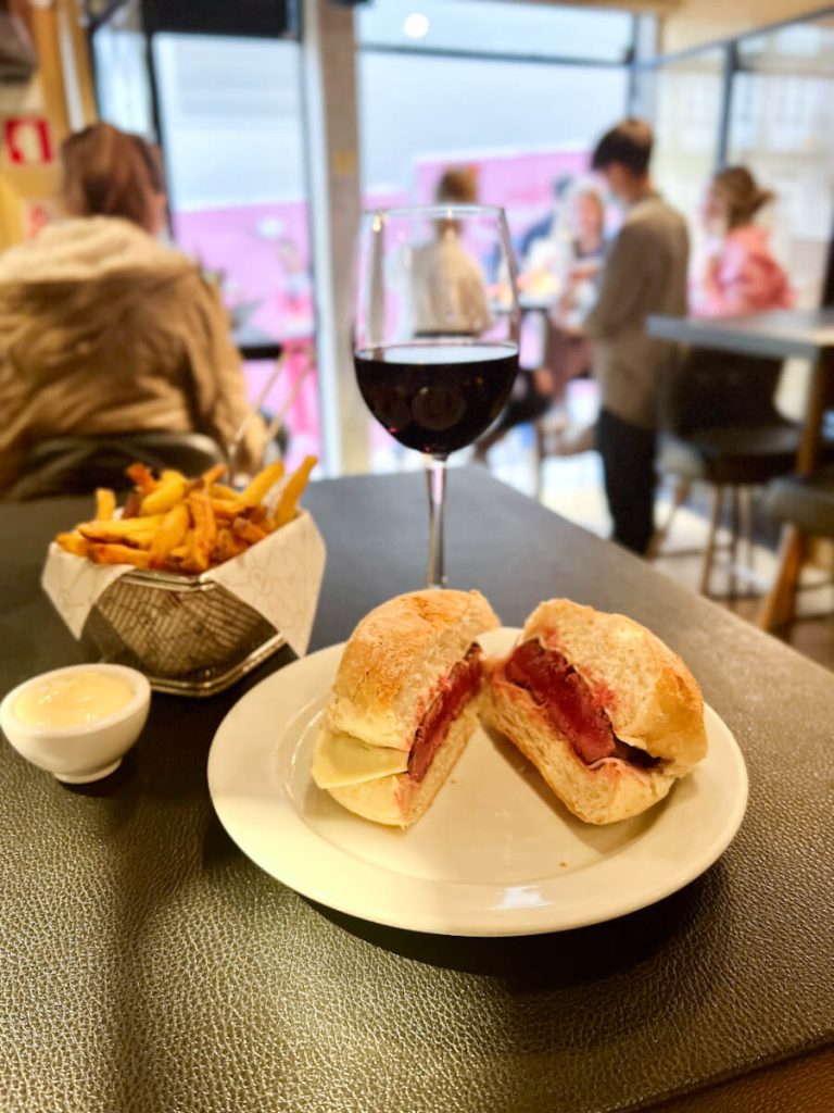 Table with Portuguese steak sandwich (prego), French fries and a glass of red wine