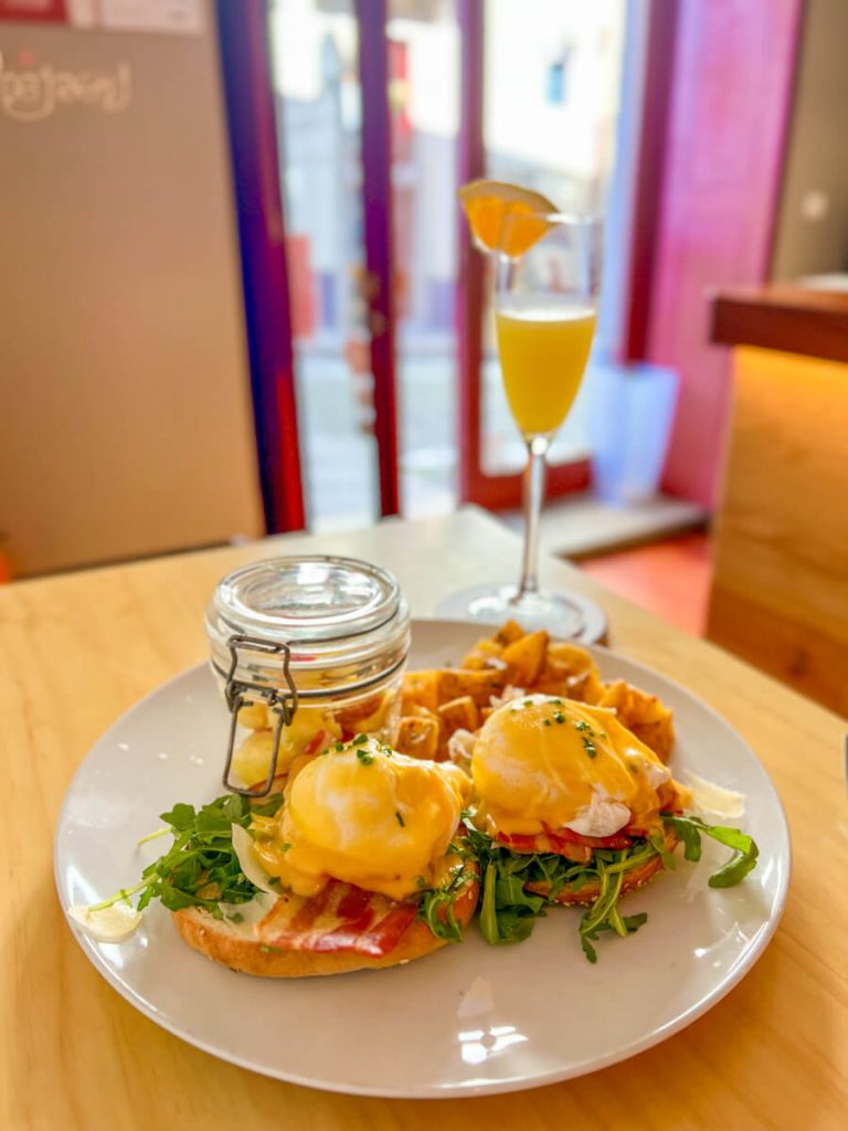 Plate of eggs Benedict and fruit and a mimosa at Swallow Brunch